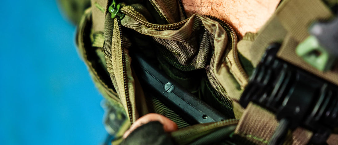 Gloved hands sliding an armor plate into a plate carrier