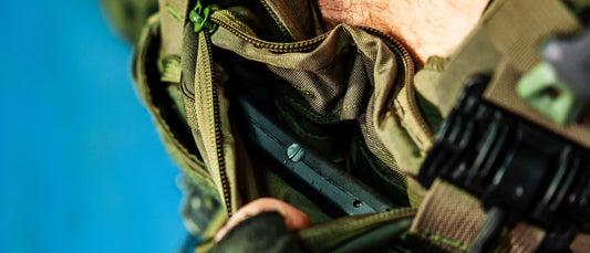 Gloved hands sliding an armor plate into a plate carrier